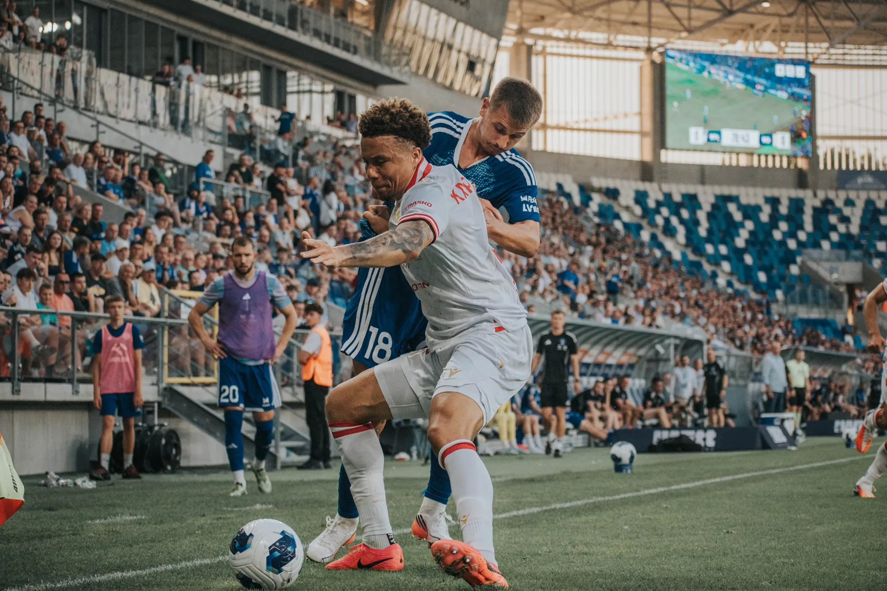 Zawodnik biegnie z piłką podczas meczu na stadionie.